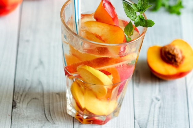 Té helado de nectarina casero o limonada con menta fresca y cubitos de hielo en vaso