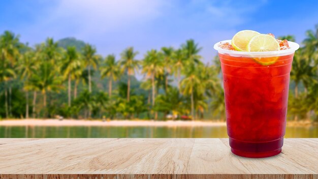 Foto té helado y rodajas de limón en la mesa de madera con fondo de naturaleza de paisaje de playa bebidas de verano con hielo