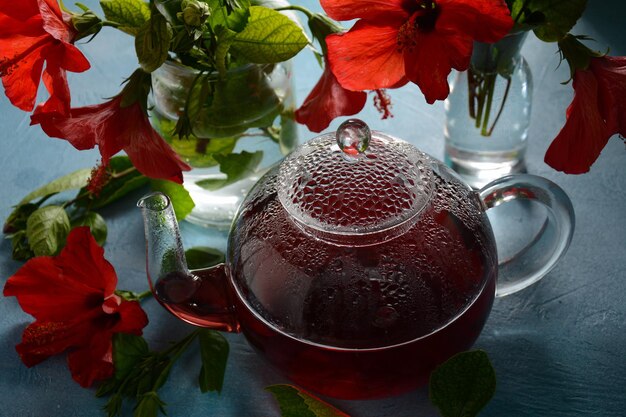 Té de hibisco en una tetera de vidrio transparente y flor en flor