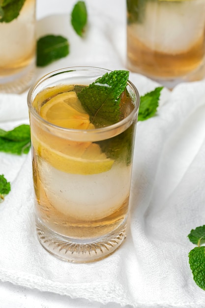 Té con hielo, menta y rodajas de limón en la mesa blanca