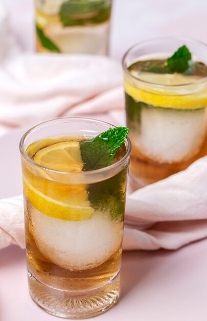 Té con hielo, menta y rodajas de limón en la mesa blanca