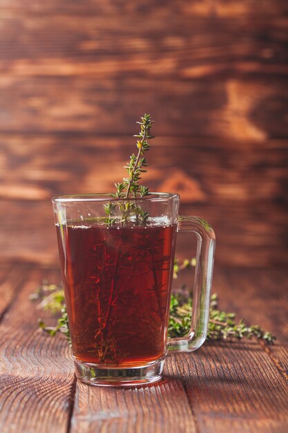 Té de hierbas aromáticas con racimos de tomillo en una taza de vidrio