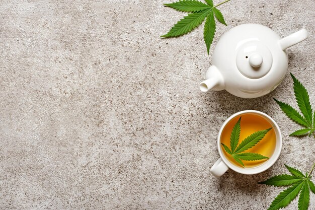 Té de hierbas de cáñamo y hojas sobre fondo gris Concepto de bebida relajante