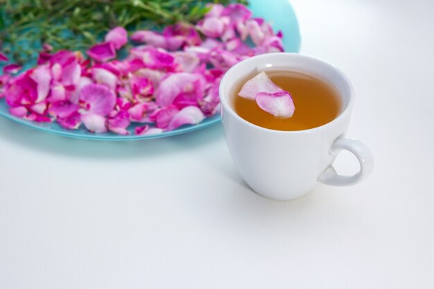 Té de hierbas casero en una taza blanca. Té de pétalos de rosa y tomillo: ingredientes para una bebida caliente y saludable