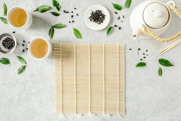 Té de hierbas con dos tazas de té blanco y una tetera con hojas de té verde Vista superior plana del concepto del té