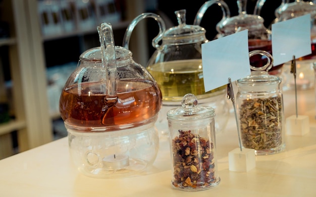 Foto té de hierbas elaborado en una tetera de vidrio y planta de té en una botella