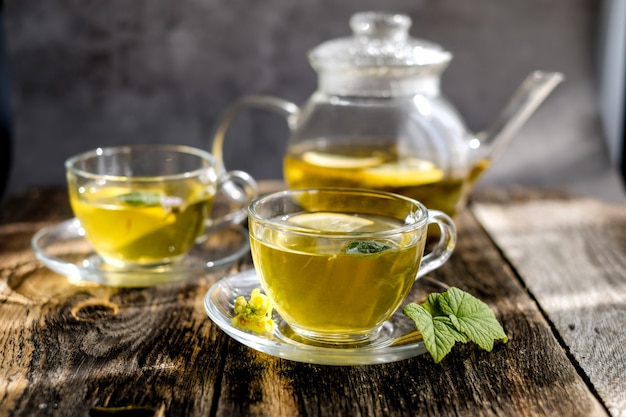 Té de hierbas con limón y miel en vaso de vidrio y tetera