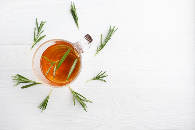 Té de hierbas con romero en una taza de vidrio sobre un fondo blanco de madera con lugar para el texto Té de romero Póster del artículo