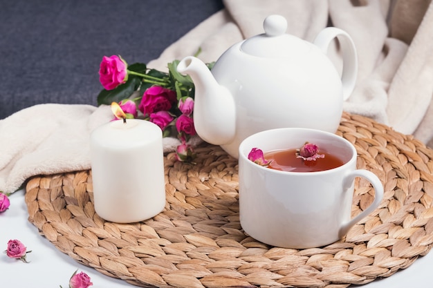 Té de hierbas, rosas rosadas y tetera en la mesa de café