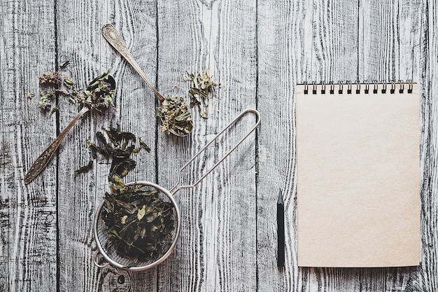 Té de hierbas secas y cuaderno vacío con lápiz