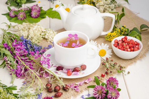 Té de hierbas en una taza blanca con flores. Ceremonia del té. Té con manzanilla, rosa silvestre y trébol