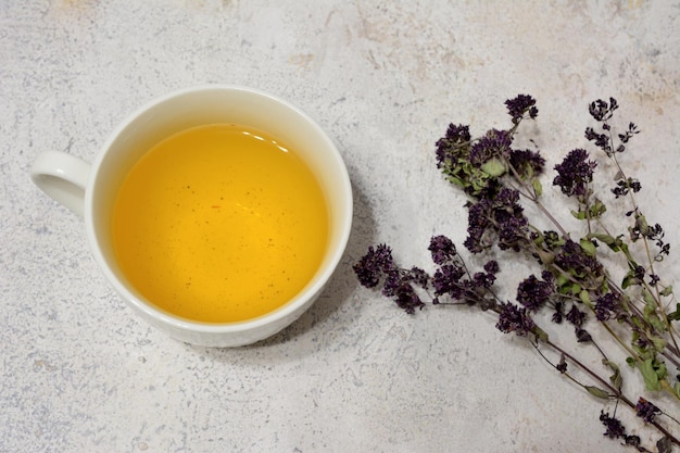 Té de hierbas en taza con plantas de mejorana seca, close-up