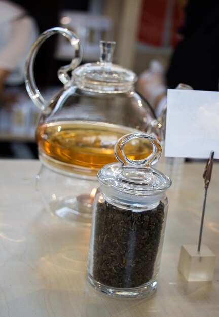 Té de hierbas en tetera y planta de té en una botella