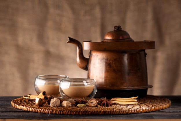 Té indio con leche y especias masala chai en una tetera y tazas de cobre