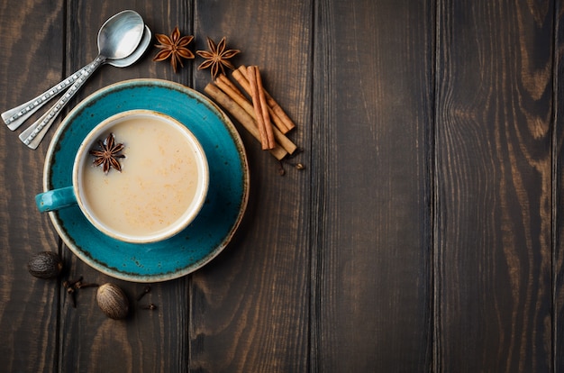 Té indio masala chai. Té especiado con leche en la mesa de madera oscura. Vista superior, plano, copia espacio.