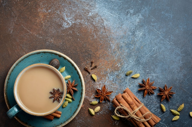 Té indio masala chai. Té especiado con leche sobre fondo oscuro oxidado