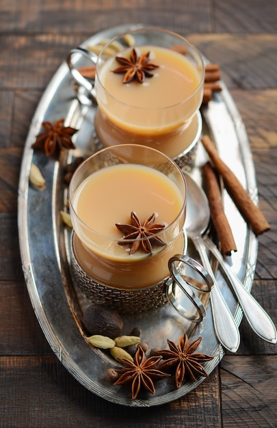 Té indio masala chai. Té con especias con leche en tazas vintage en la rústica mesa de madera.