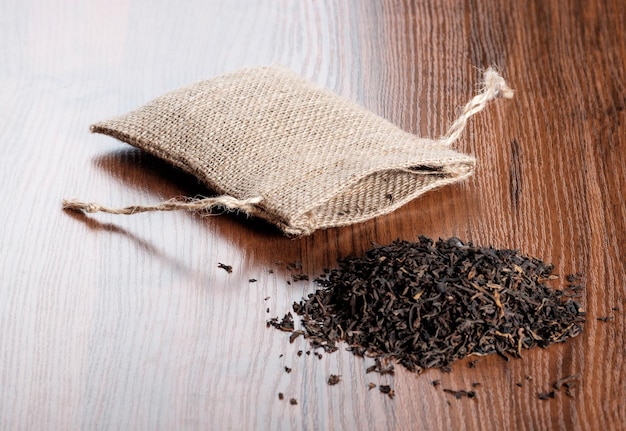 Té indio negro seco con bolsa de arpillera vintage sobre fondo de madera