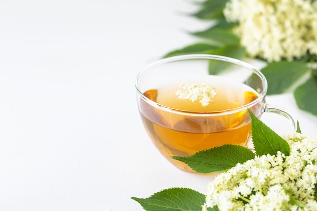 Té y jarabe de flores de saúco Sambucus sobre un fondo blanco. Copia espacio