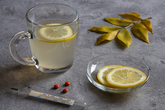 Té de jengibre con limón, limón y hojas en gris