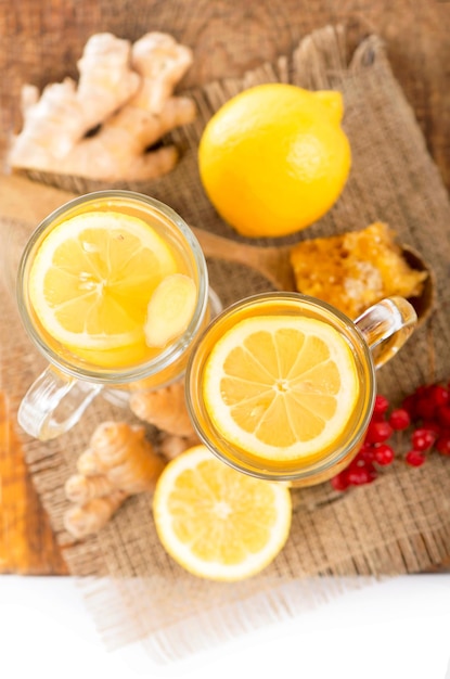 Té de jengibre con limón y miel en vaso de cristal sobre mesa de madera