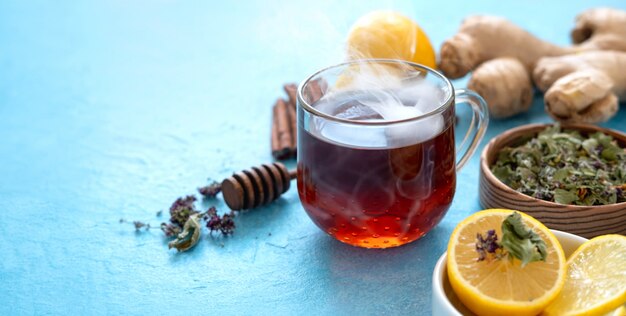 Té de jengibre con limón en un vaso en la superficie azul