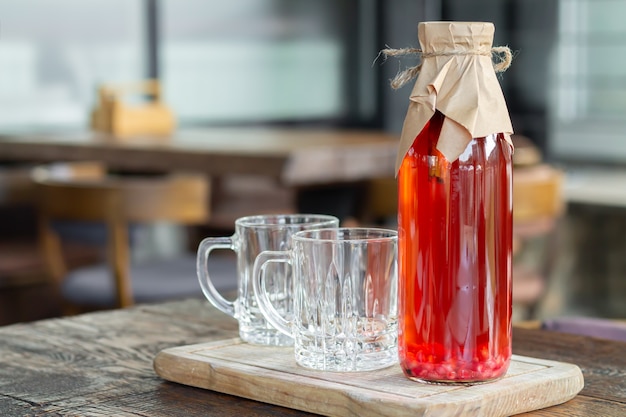 Té de Kombucha con frutos rojos en botella de vidrio junto a vasos de vidrio. Bebida fermentada saludable