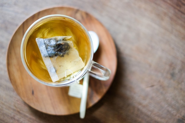 El té de lavanda caliente en vidrio se sirve con una cuchara y un platillo de madera.