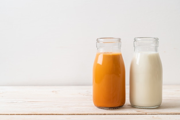 Té de leche tailandesa con leche fresca en botella en madera