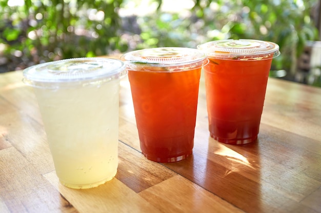 Té de limón helado y soda de miel y limón en vasos de plástico con tapas colocadas sobre mesas de madera Bebidas herbales tailandesas