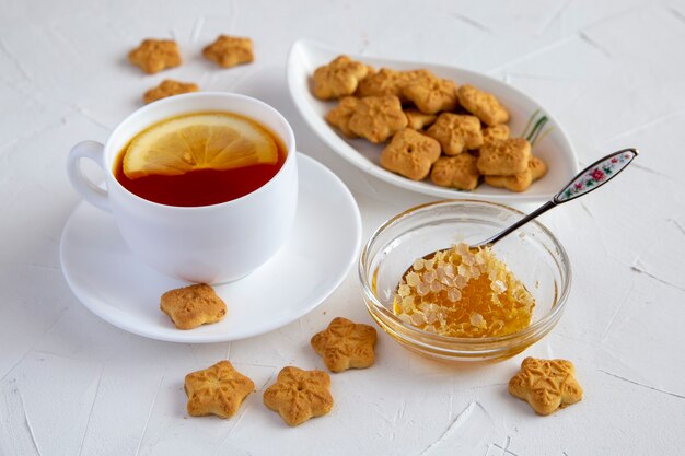 Té de limón, panal de miel y galletas sobre una mesa blanca