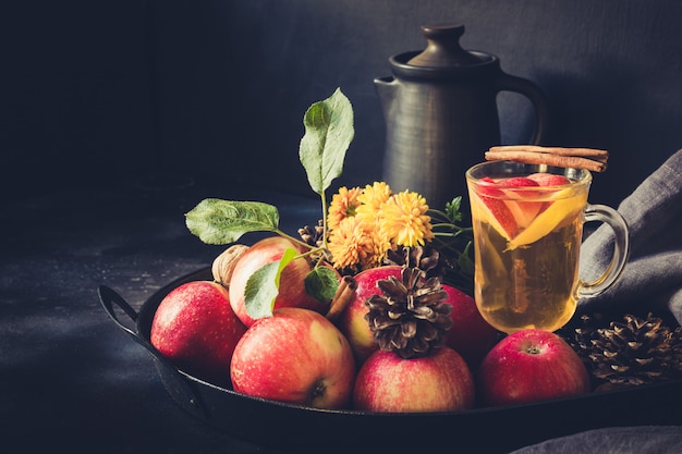 Té de manzana con limón, especias y canela en bandeja vintage en pizarra. Bodegón otoñal. De cerca.