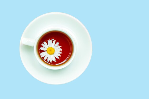 Té de manzanilla en una taza blanca sobre un fondo amarillo