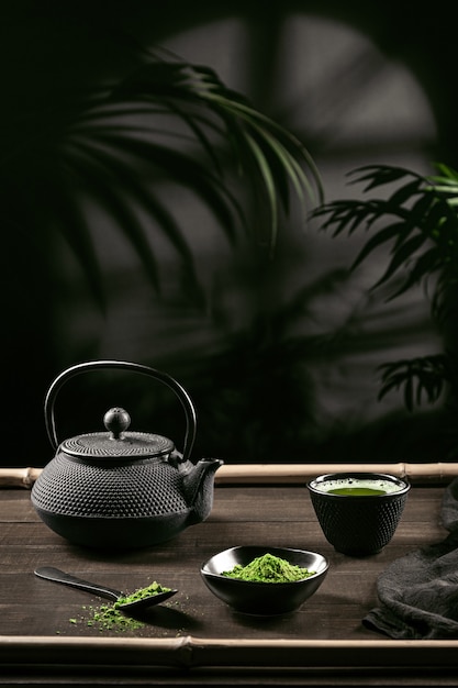 Té matcha en polvo y accesorios para té sobre base de madera oscura. Ceremonia del té. Bebida tradicional japonesa. Formato vertical.