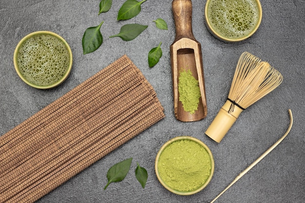 Té matcha en polvo en un tazón Té matcha y una servilleta de palo de madera Batidor de bambú y cuchara para hacer té Fondo plano negro