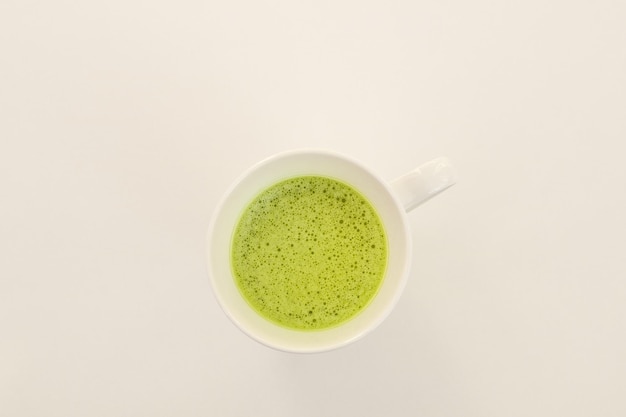 Té matcha en una taza blanca sobre un fondo blanco. Lugar para el texto.