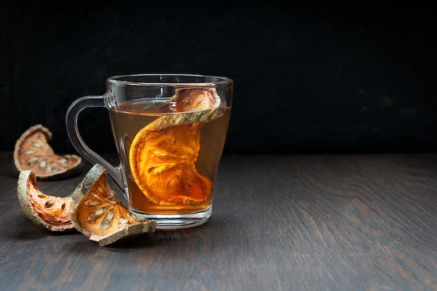 Té matoom tailandés hecho de rodajas de frutas secas de bael en un vaso sobre la mesa de madera de color marrón oscuro