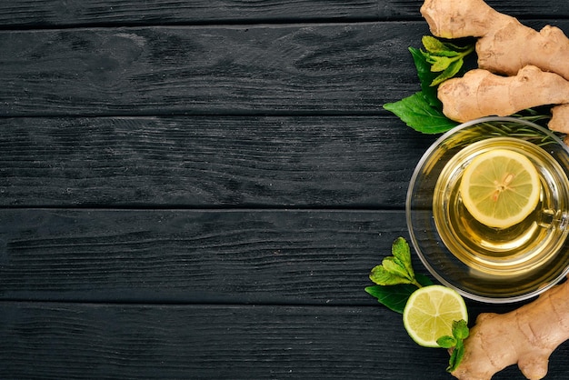 Té con menta, jengibre y limón. Bebida caliente sobre un fondo de madera. Vista superior. Copie el espacio.