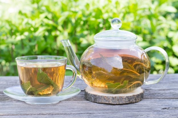 Té de menta en una tetera y una taza al aire libre