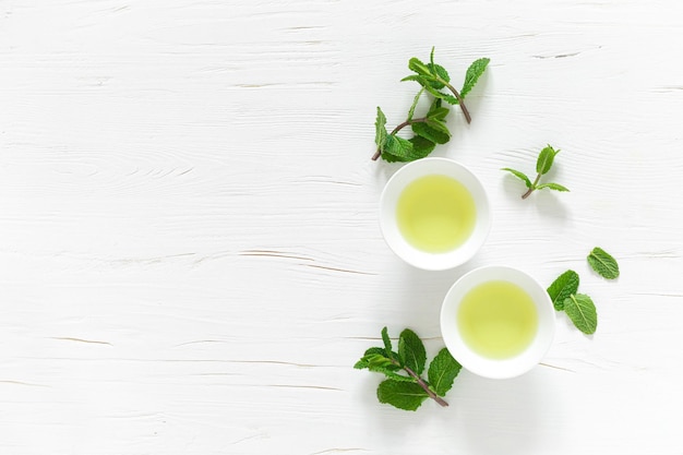 Té de menta verde con hojas frescas en tazas y tetera sobre una mesa de madera blanca bebida de calentamiento saludable bebida antioxidante vista superior