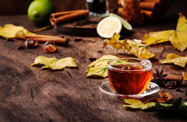 Té negro caliente de otoño en vaso de vidrio mesa de madera vieja fondo enfoque selectivo