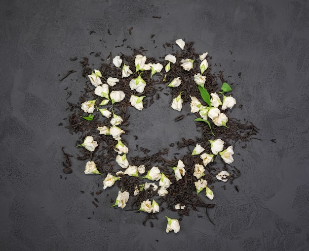 Té negro con flores secas de jazmín en una textura negra