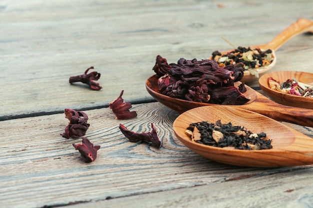 Té negro con hierbas en cucharas de madera sobre una plancha de madera