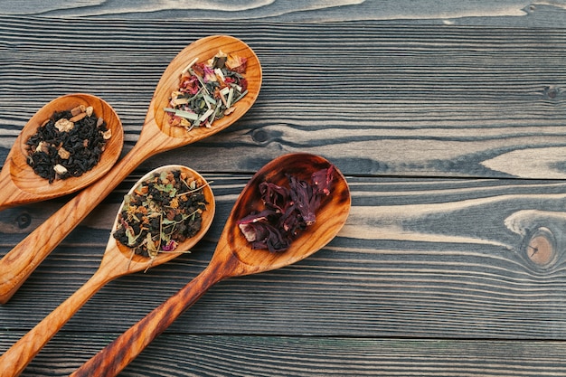 Té negro con hierbas en cucharas de madera sobre una plancha de madera