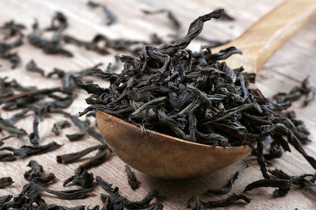 Té negro hojas de té negro en una cuchara de madera closeup