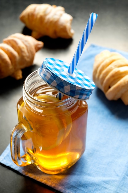 Té negro con limón en jarra y galletas