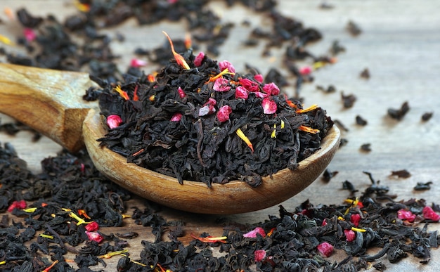 té negro mezclado con pétalos de flores y frutos secos en una cuchara de madera.