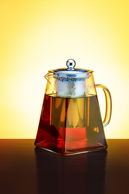 Té negro en una tetera de vidrio sobre una mesa de madera oscura Imagen vertical