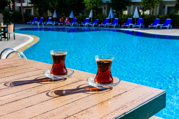 Té negro en vasos tradicionales turcos en la mesa cerca de la piscina