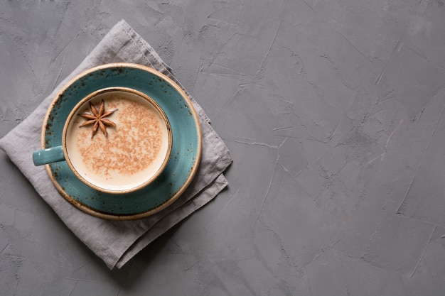 Té o café indio Masala en taza azul con especias y canela en negro. Vista superior.